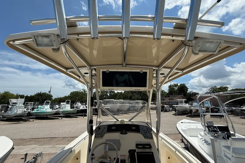 Slide: The Image of 2008 Scout 222 Sportfish boat console with T-top, parked in a marina under a blue sky. - 11