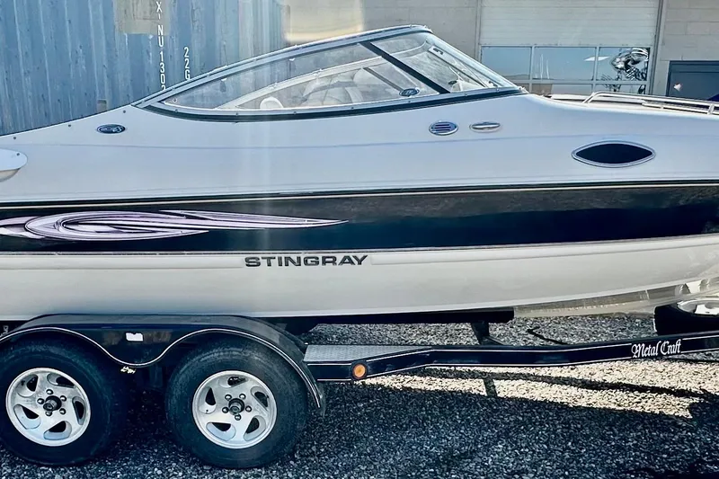 Slide: The Image of 2010 Stingray 205 CS/CX boat on trailer, side view, parked outdoors. - 2
