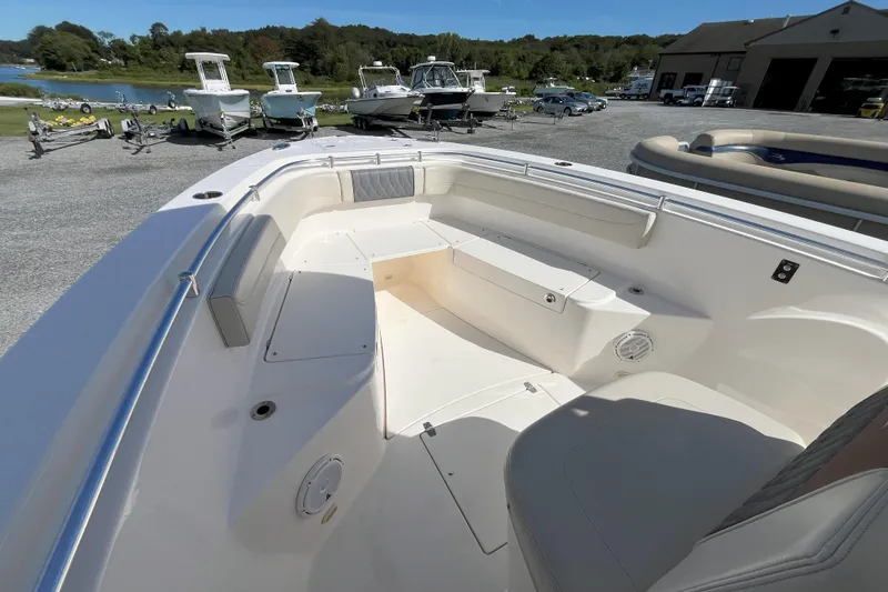 Slide: The Image of 2019 Cobia 277 Center Console boat interior with seating, docked near other boats. - 11