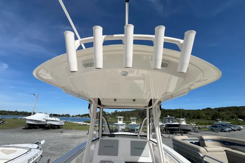 Slide: The Image of 2019 Cobia 277 Center Console boat with rod holders, parked near a scenic waterfront. - 4
