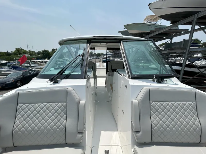 Slide: The Image of 2026 Pursuit DC 326 boat with sleek design and comfortable seating in a marina setting. - 19