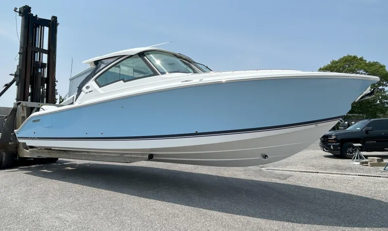 Slide: The Image of 2026 Pursuit DC 326 boat lifted by forklift in a parking area. - 4