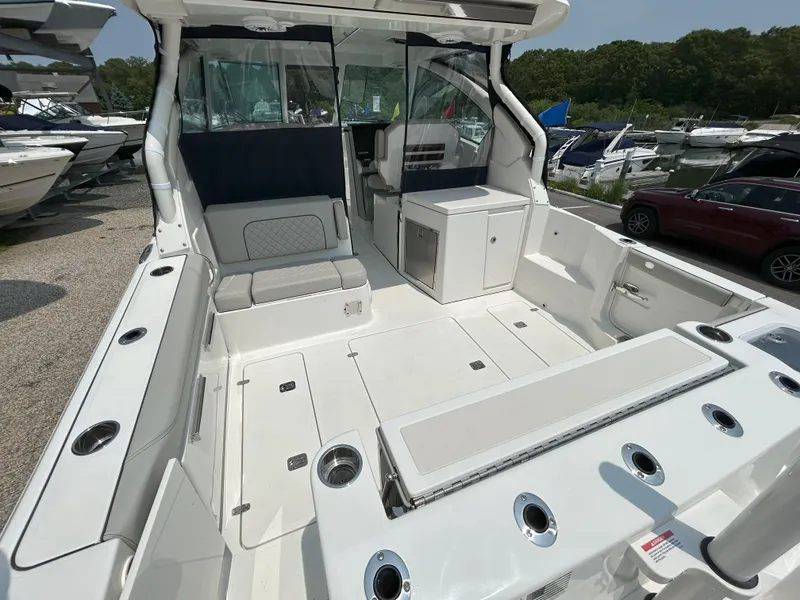 Slide: The Image of 2026 Pursuit DC 326 boat interior with seating and storage, docked among other boats. - 7