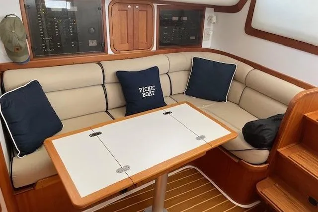 Slide: The Image of 2003 Legacy Yachts 34 Express interior with beige seating, table, and nautical-themed cushions. - 20