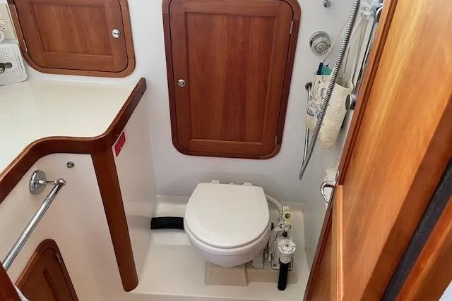 Slide: The Image of 2003 Legacy Yachts 34 Express bathroom with wooden cabinetry and compact toilet. - 22