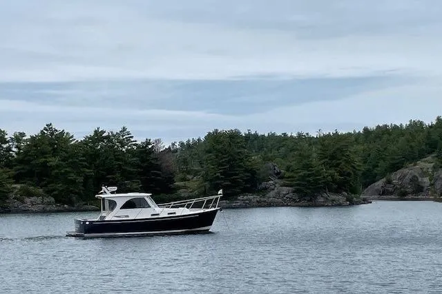 Slide: The Image of 2003 Legacy Yachts 34 Express cruising on a serene lake with lush green trees. - 41