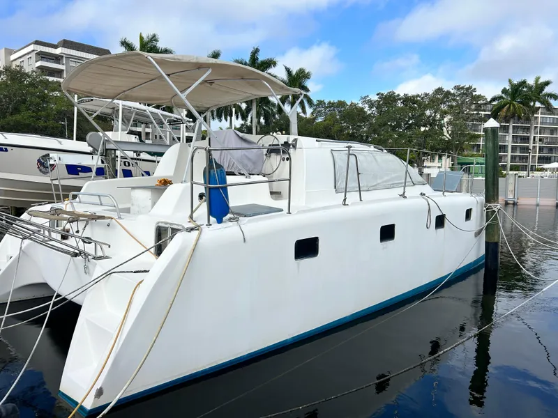 The Image of 2004 Endeavour Catamaran Victory docked at marina with blue skies and palm trees. - 0