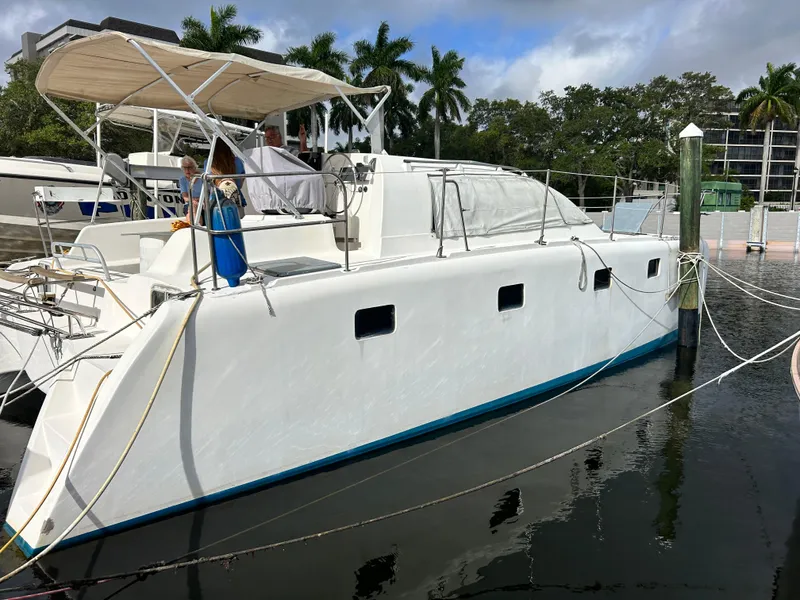 Slide: The Image of 2004 Endeavour Catamaran Victory docked at marina with palm trees in background. - 2
