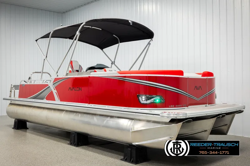 Slide: The Image of 2026 Avalon LSZ VRB pontoon boat, red with black canopy, displayed indoors. - 3