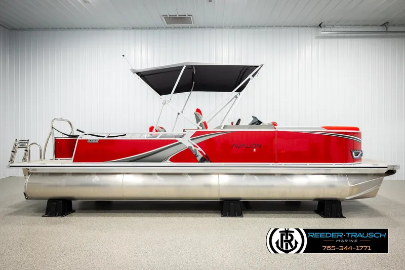 Slide: The Image of 2026 Avalon LSZ VRB pontoon boat in a showroom, featuring a sleek red design. - 5