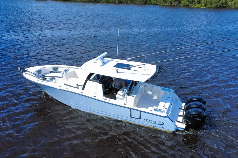 Slide: The Image of 2022 Robalo R360 Center Console boat cruising on a calm blue lake. - 14