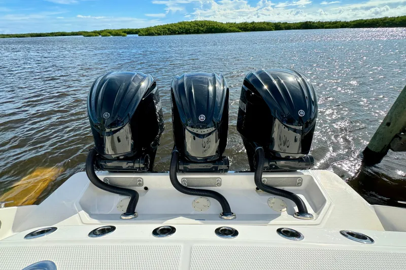 Slide: The Image of Triple outboard engines on a 2022 Robalo R360 Center Console boat, docked by the water. - 19