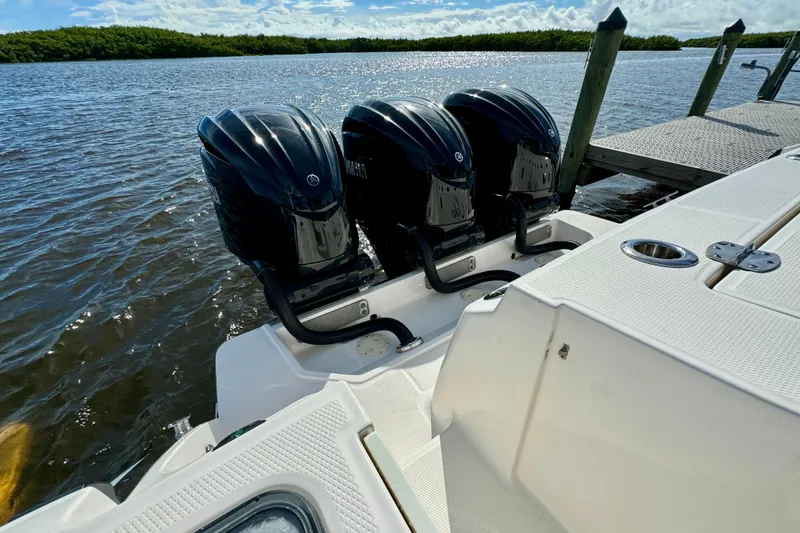Slide: The Image of 2022 Robalo R360 Center Console with triple outboard engines docked by the water. - 20