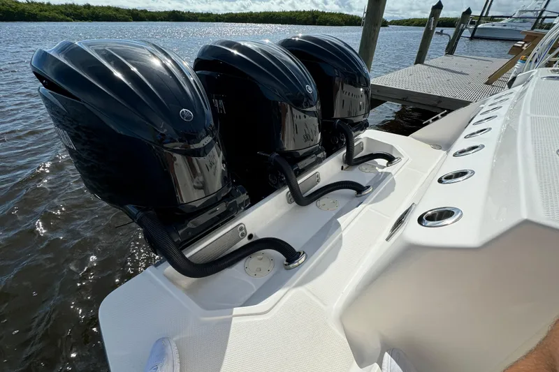 Slide: The Image of Triple outboard engines on a 2022 Robalo R360 Center Console boat docked by the water. - 22