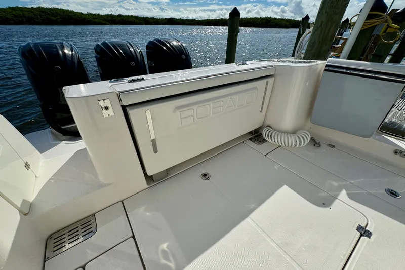 Slide: The Image of 2022 Robalo R360 Center Console boat with triple outboard engines docked by the water. - 25
