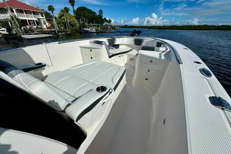 Slide: The Image of 2022 Robalo R360 Center Console boat interior with seating and storage, docked by waterfront homes. - 33