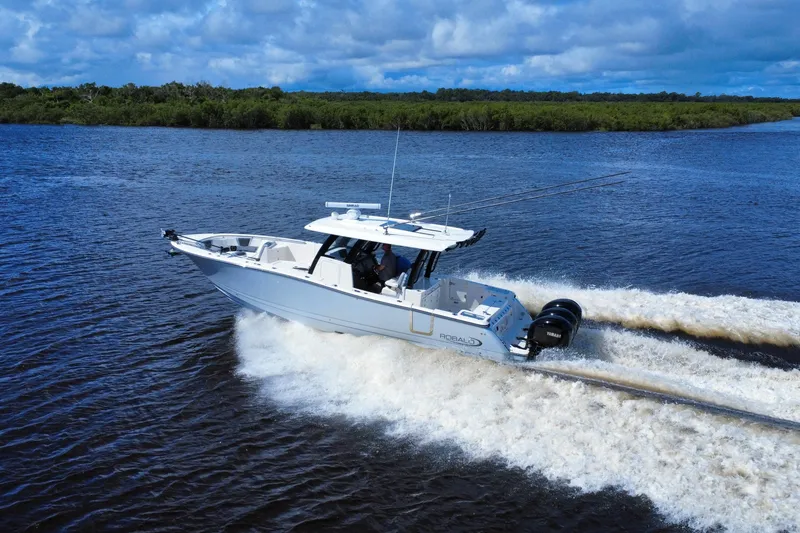 Slide: The Image of 2022 Robalo R360 Center Console boat cruising on a river under a cloudy sky. - 8