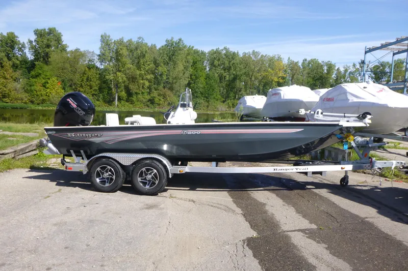 The Image of 2024 Ranger RB200 boat on trailer, parked near a lake with trees in the background. - 1