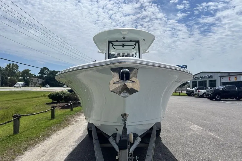 Slide: The Image of 2021 Sea Hunt Gamefish 25 boat on trailer, parked near showroom under cloudy sky. - 2