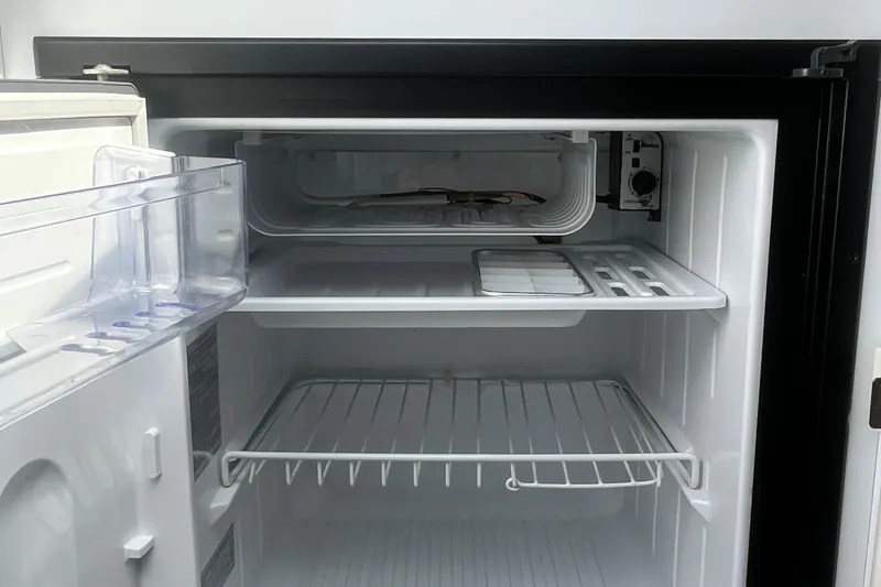 Slide: The Image of Open refrigerator interior with empty shelves and freezer compartment. - 21