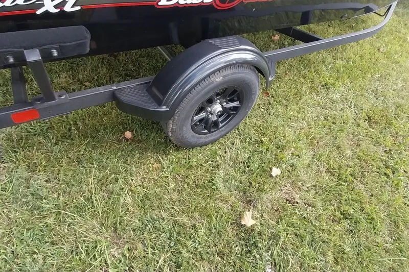 Slide: The Image of 2023 Tracker Bass Tracker Classic XL trailer wheel on grass. - 24