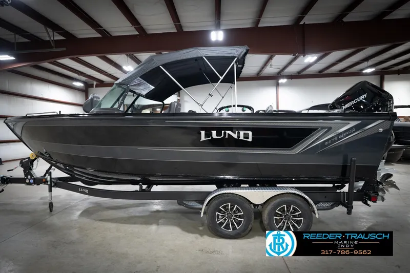 Slide: The Image of 2026 Lund 2275 Baron boat in showroom, featuring sleek black design and Mercury engine. - 11