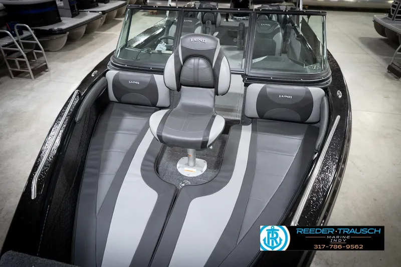 Slide: The Image of 2026 Lund 2275 Baron boat interior with gray seating and windshield in showroom. - 12