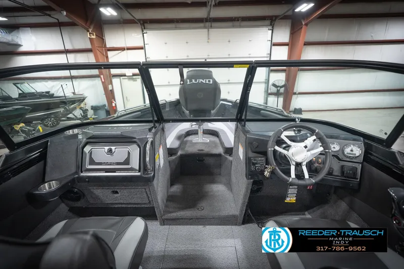Slide: The Image of 2026 Lund 2275 Baron boat interior with steering wheel and dashboard in a showroom. - 17