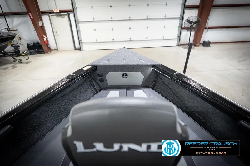 Slide: The Image of 2026 Lund 2275 Baron boat interior in a showroom, featuring seating and storage. - 18