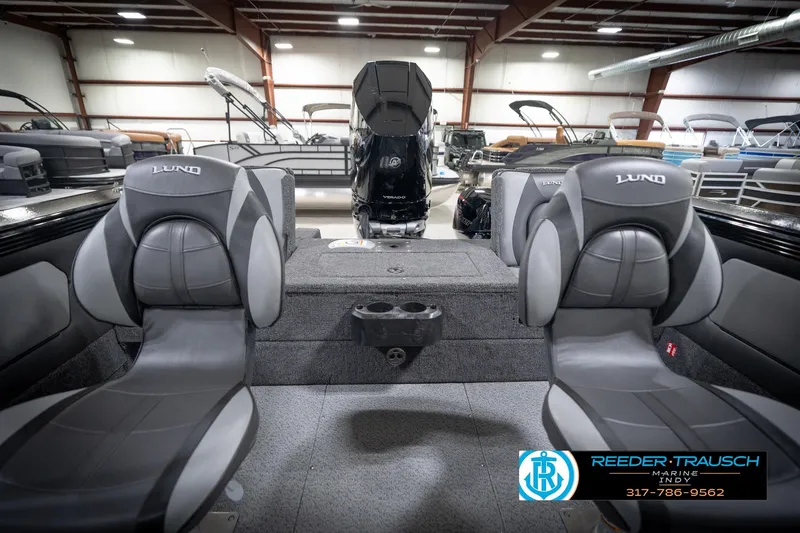Slide: The Image of 2026 Lund 2275 Baron boat interior with seating and motor, displayed in a showroom. - 21