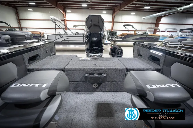 Slide: The Image of 2026 Lund 2275 Baron boat interior with seating and motor in showroom. - 22