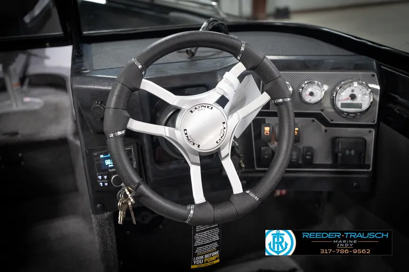 Slide: The Image of Steering wheel and dashboard of 2026 Lund 2275 Baron boat, featuring modern controls. - 36