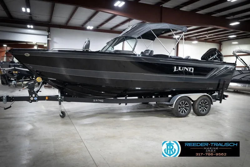 Slide: The Image of 2026 Lund 2275 Baron boat on trailer in indoor showroom, featuring sleek black design. - 4