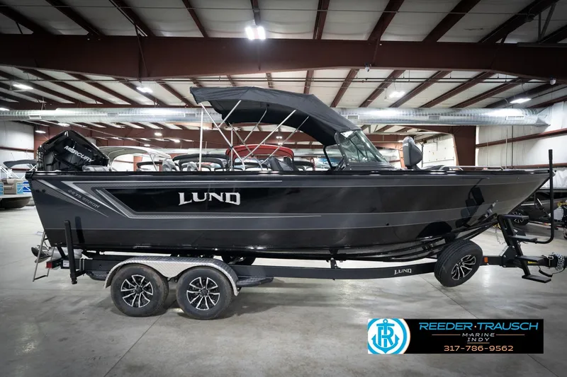 Slide: The Image of 2026 Lund 2275 Baron boat in showroom, side view with trailer. - 7