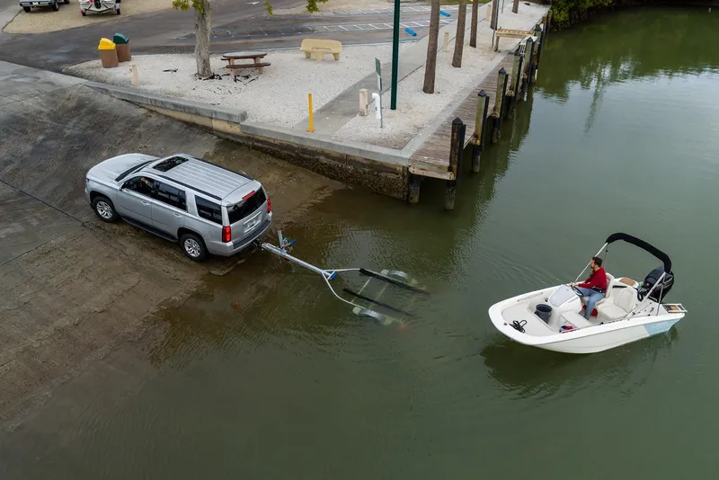 Slide: The Image of 2026 Boston Whaler 130 Super Sport being launched from a trailer at a boat ramp. - 2