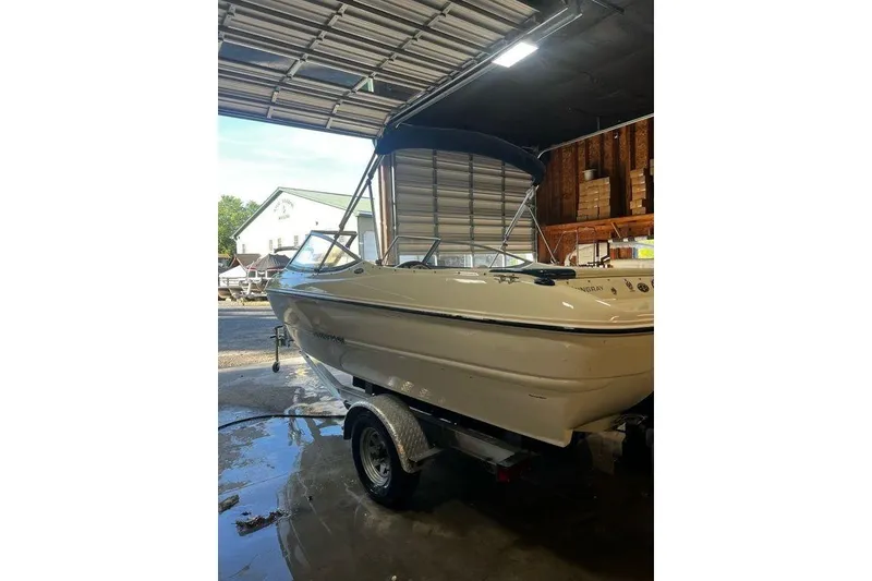 Slide: The Image of 2013 Stingray 195RX boat in a garage, on a trailer, with a blue canopy. - 2