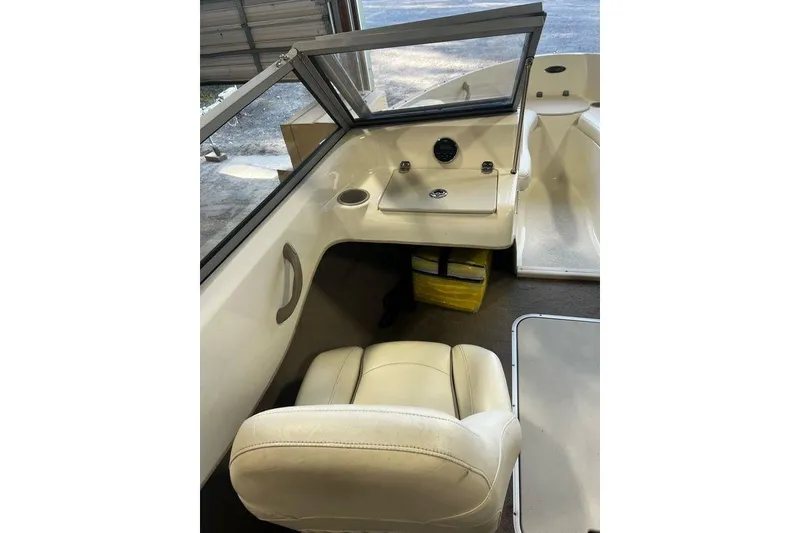 Slide: The Image of 2013 Stingray 195RX boat interior with beige seating and dashboard controls. - 7