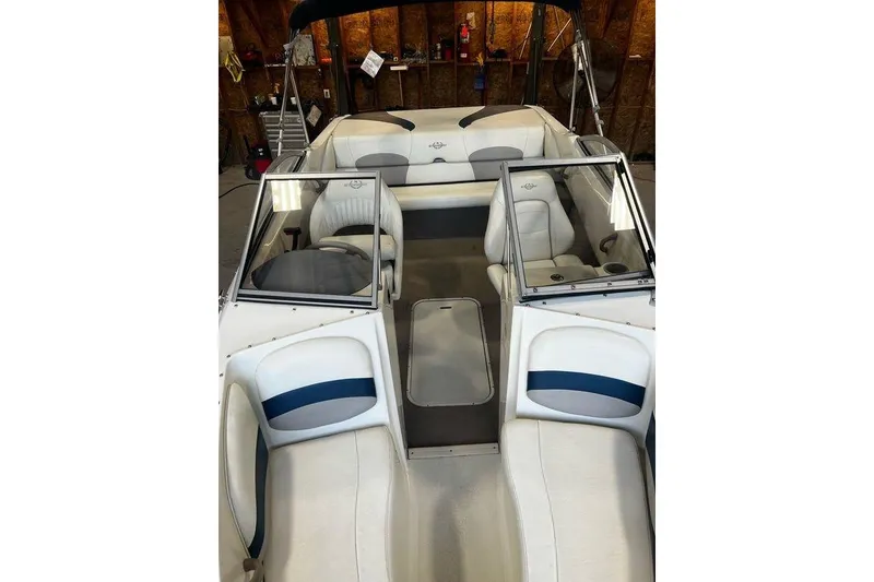 Slide: The Image of 2013 Stingray 195RX boat interior with white and blue seating, in a garage setting. - 8