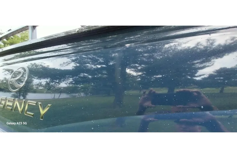 Slide: The Image of 2022 Regency 250 DL3 boat with reflective surface and logo, photographed outdoors. - 11