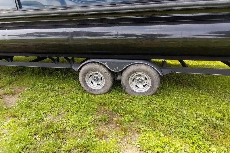 Slide: The Image of 2022 Regency 250 DL3 boat trailer on grassy terrain, showcasing dual wheels. - 16