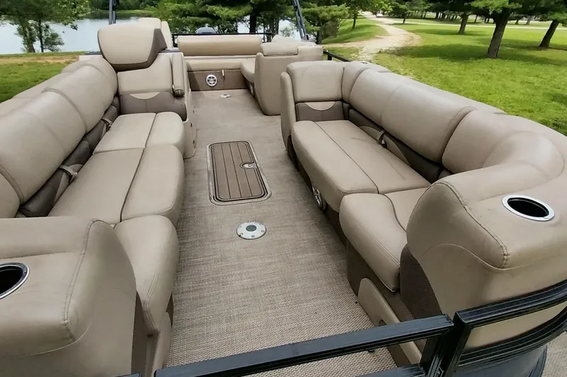 Slide: The Image of 2022 Regency 250 DL3 pontoon boat with spacious beige seating and cup holders. - 2