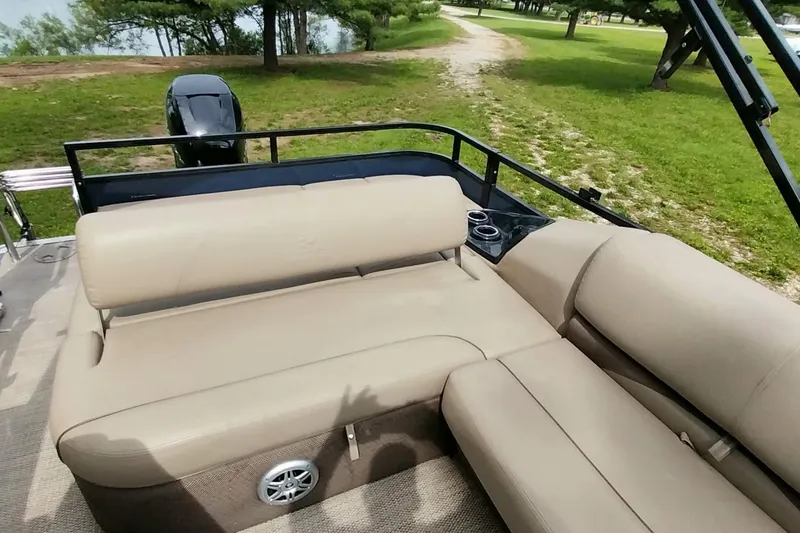 Slide: The Image of 2022 Regency 250 DL3 pontoon boat with beige seating, cup holders, and scenic lake view. - 3