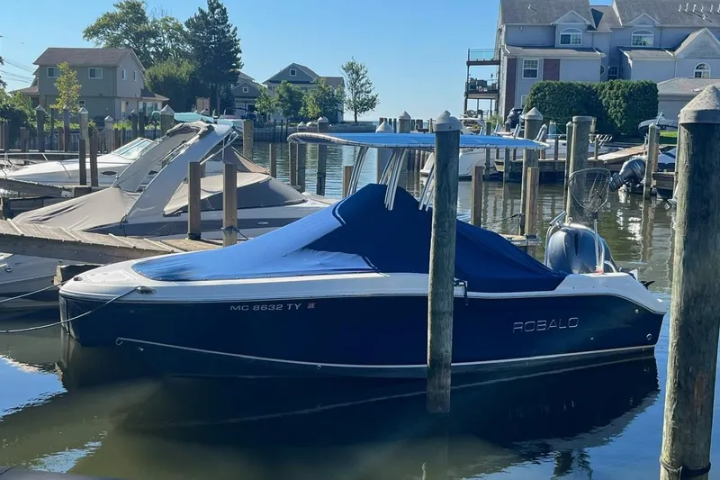 Slide: The Image of 2017 Robalo R200 Center Console boat docked in a marina, covered and ready for use. - 2