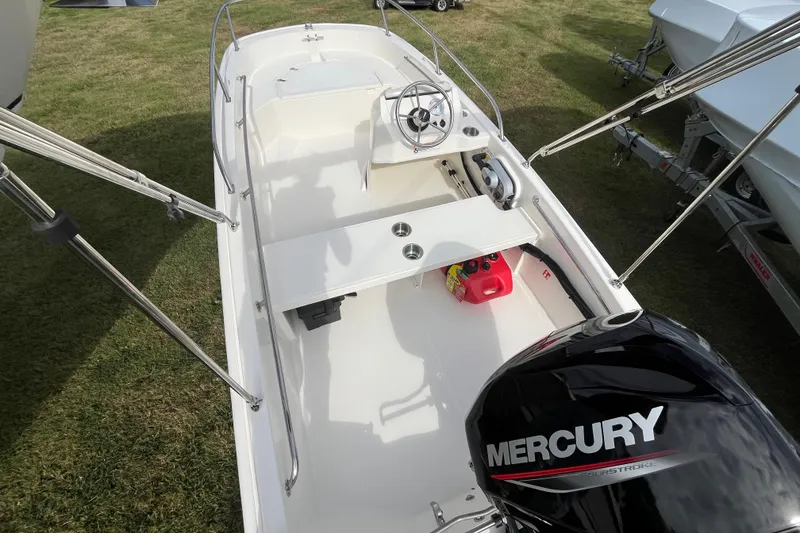 Slide: The Image of 2026 Boston Whaler 130 Super Sport boat with Mercury engine on grassy display. - 3