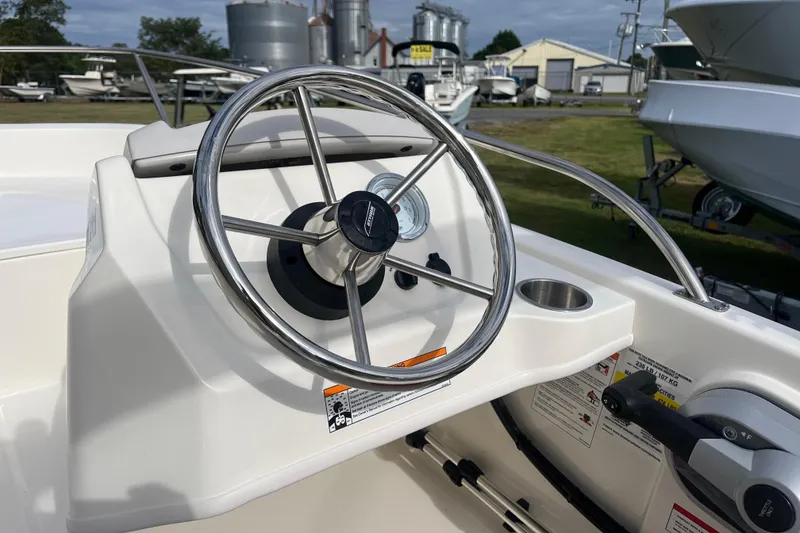 Slide: The Image of Steering wheel of 2026 Boston Whaler 130 Super Sport boat, showcasing dashboard controls. - 9