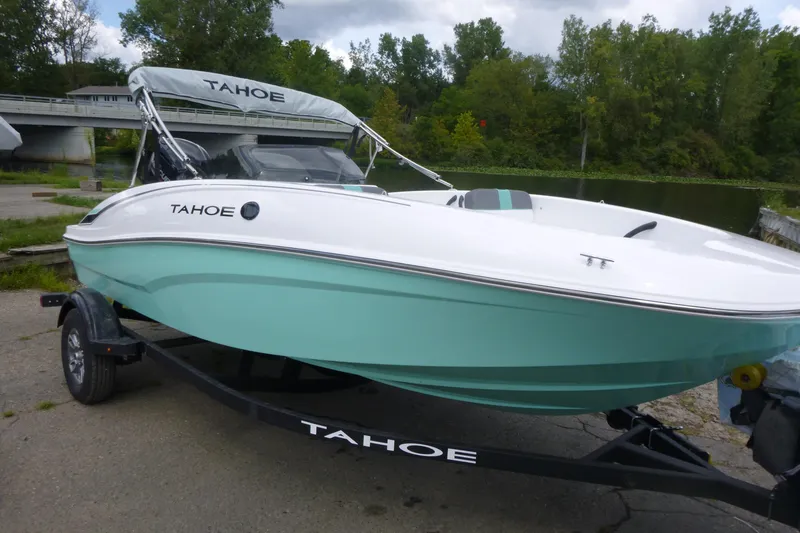 Slide: The Image of 2026 Tahoe T16 boat on trailer by a river, featuring sleek design and mint green hull. - 3
