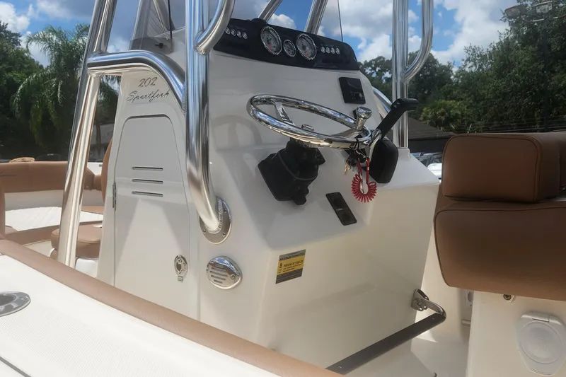 Slide: The Image of 2026 Pioneer 202 Sportfish boat console with steering wheel and controls, set against a sunny backdrop. - 6