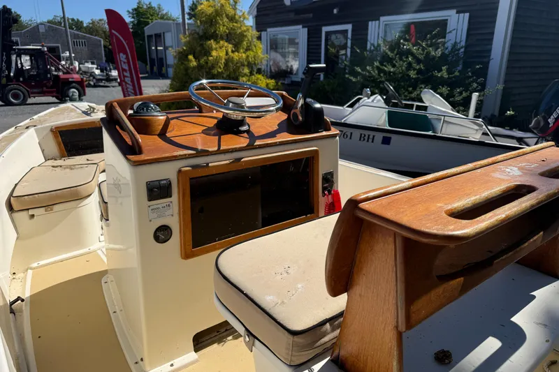 Slide: The Image of 2003 Roth Bilt 16 Skiff boat interior with wooden helm and cushioned seating. - 4
