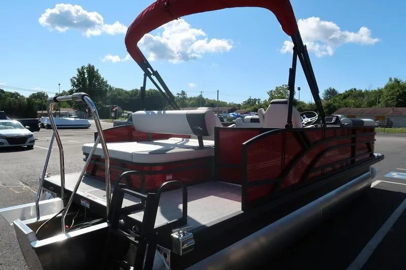 Slide: The Image of 2026 Bennington S Swingback 22 SSB SPS pontoon boat with red canopy in parking lot. - 3