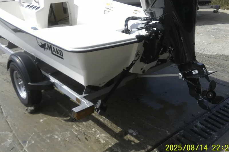 Slide: The Image of 2024 Mako Pro Skiff 15 CC on trailer, featuring outboard motor, parked on concrete surface. - 3